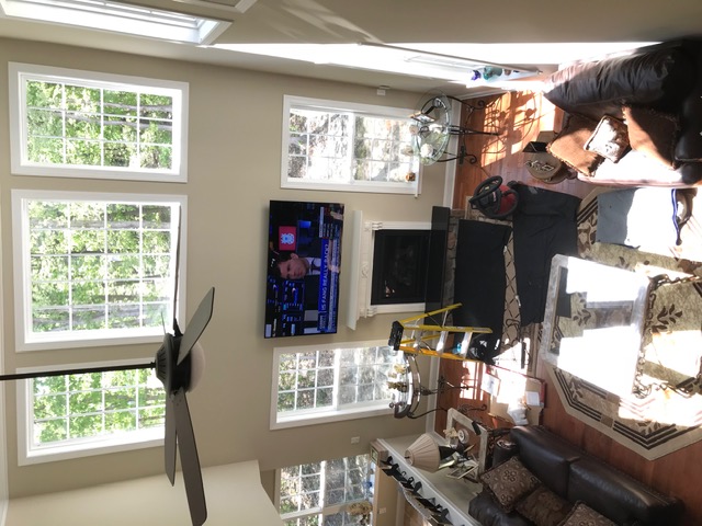 Two-story great room with a TV mounted over the fireplace between tall windows